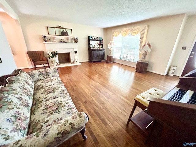 living room featuring a textured ceiling, wood-type flooring, and a high end fireplace