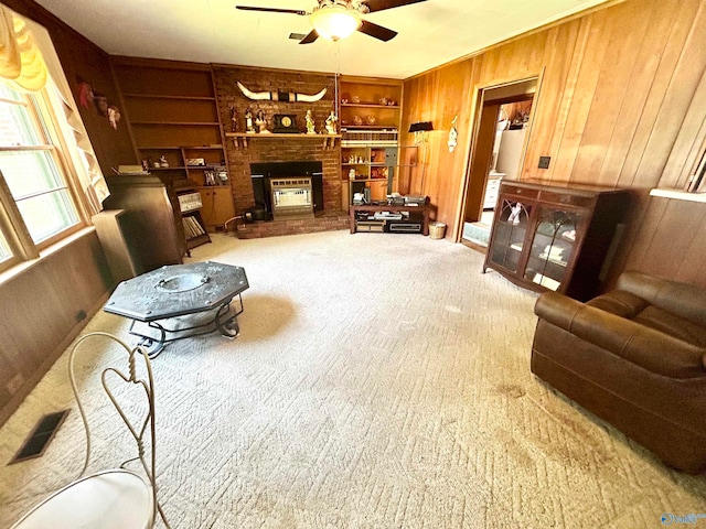 carpeted living room featuring a fireplace, built in features, wooden walls, and ceiling fan