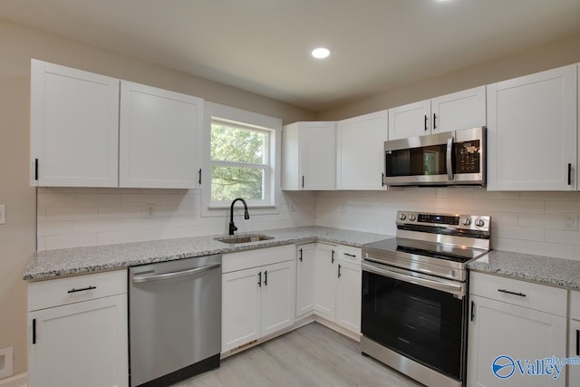 kitchen featuring stainless steel appliances, light hardwood / wood-style floors, light stone counters, and tasteful backsplash