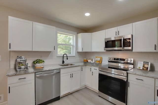 kitchen featuring appliances with stainless steel finishes, light hardwood / wood-style floors, white cabinetry, and tasteful backsplash