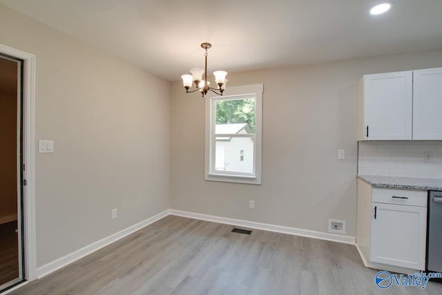 unfurnished dining area with a notable chandelier and light hardwood / wood-style flooring