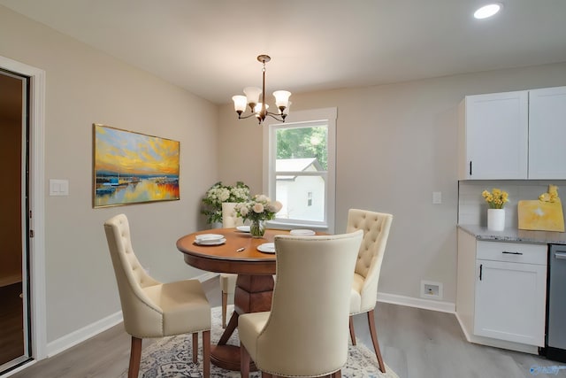 dining space with light wood-type flooring and a notable chandelier