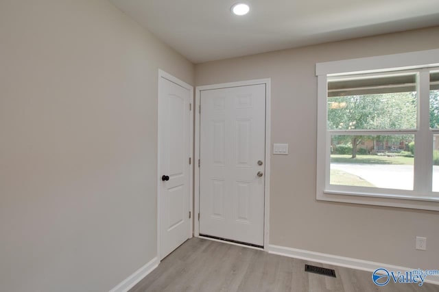 doorway to outside with baseboards, visible vents, and light wood finished floors