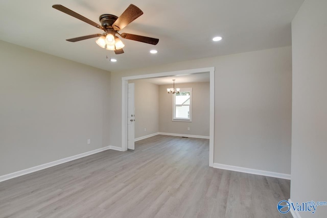 spare room featuring light wood-type flooring and ceiling fan with notable chandelier