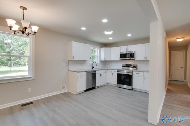 kitchen featuring light wood-type flooring, plenty of natural light, decorative backsplash, and stainless steel appliances