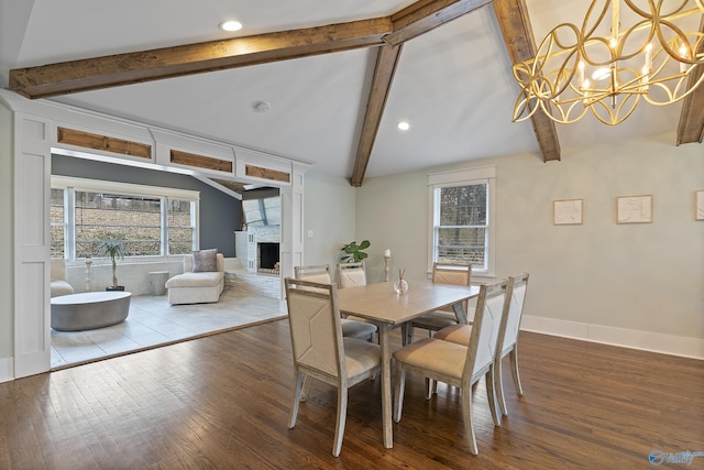 dining space with hardwood / wood-style flooring, a fireplace, a chandelier, and vaulted ceiling with beams