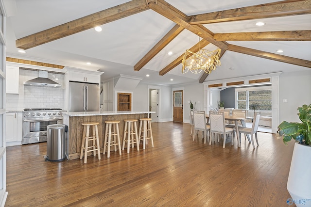 kitchen with stainless steel appliances, a center island, white cabinets, and wall chimney exhaust hood