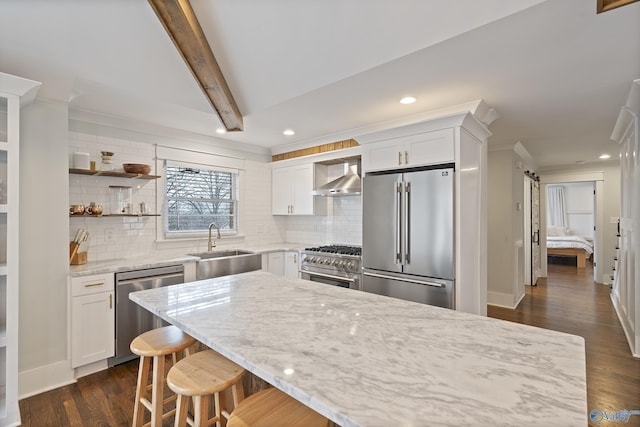 kitchen with sink, light stone counters, white cabinets, and premium appliances