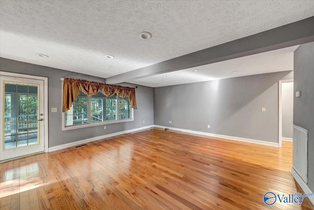 interior space with light hardwood / wood-style floors, beamed ceiling, and a wealth of natural light