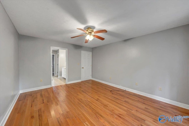 unfurnished bedroom featuring ensuite bathroom, light hardwood / wood-style flooring, a textured ceiling, and ceiling fan