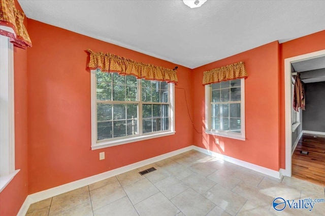 empty room featuring a textured ceiling and tile patterned flooring