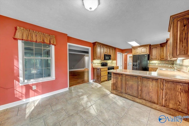 kitchen with decorative backsplash, kitchen peninsula, sink, black appliances, and a textured ceiling