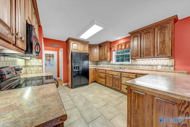 kitchen with light tile patterned floors, black appliances, sink, and backsplash