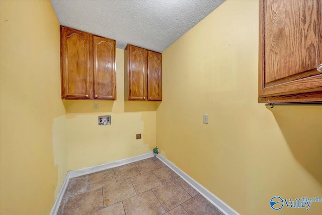 clothes washing area featuring cabinets, hookup for a washing machine, a textured ceiling, and light tile patterned floors