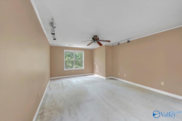 empty room featuring ceiling fan, ornamental molding, track lighting, and light colored carpet