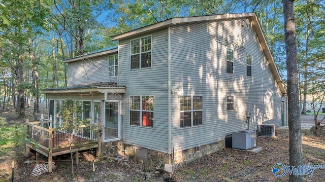 rear view of house featuring a wooden deck, central air condition unit, and a sunroom