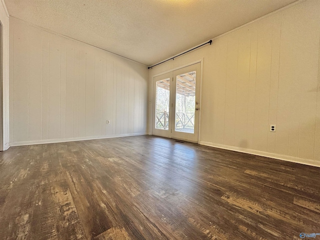 unfurnished room with wooden walls, a textured ceiling, and dark hardwood / wood-style flooring