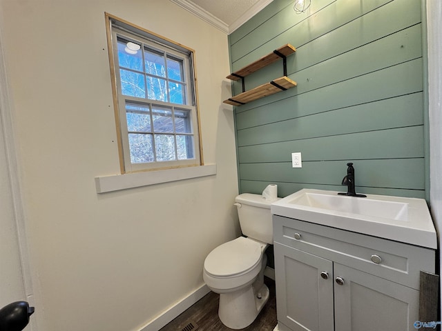 bathroom featuring wood walls, wood-type flooring, ornamental molding, vanity, and toilet