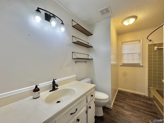 full bathroom with hardwood / wood-style floors, ornamental molding, vanity, toilet, and a textured ceiling