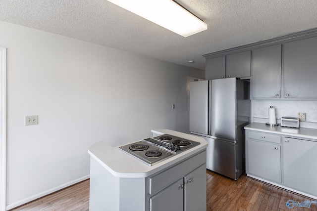 kitchen with gray cabinetry, wood finished floors, and stainless steel appliances