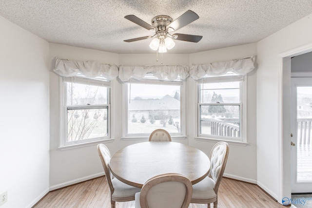 dining room featuring a textured ceiling, light wood-type flooring, and baseboards