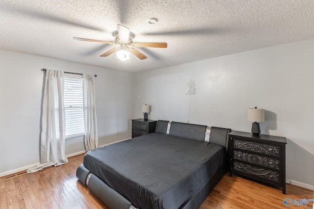 bedroom with a textured ceiling, a ceiling fan, baseboards, and wood finished floors