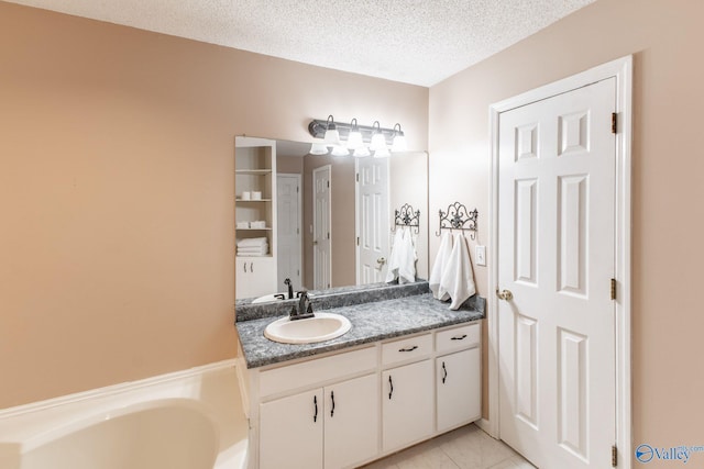 bathroom with tile patterned floors, a textured ceiling, vanity, and a garden tub