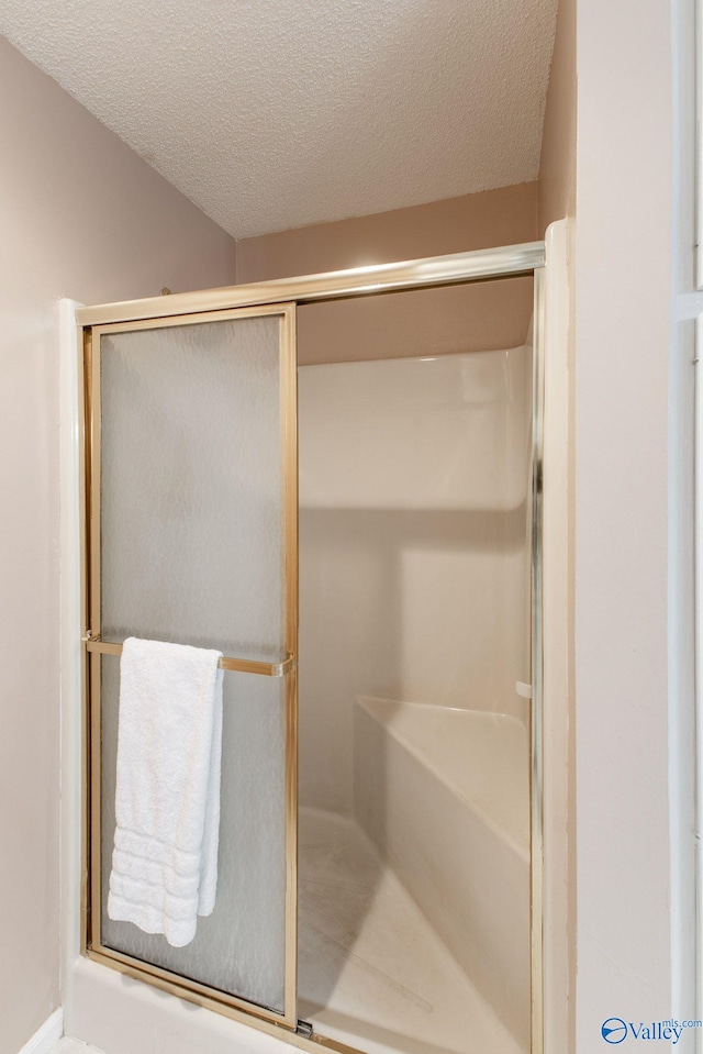 full bath with a shower stall and a textured ceiling