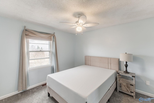 bedroom with a ceiling fan, baseboards, dark carpet, and a textured ceiling