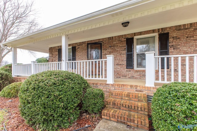 property entrance with a porch and brick siding