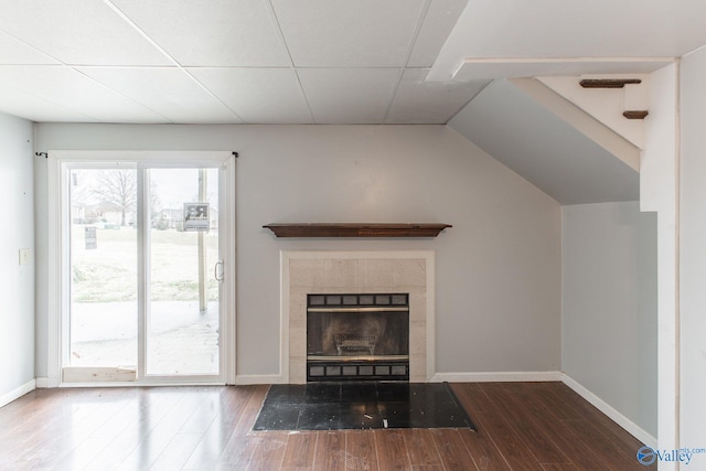 unfurnished living room featuring a tiled fireplace, wood finished floors, and baseboards