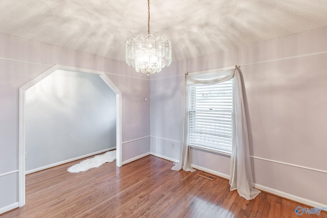 interior space featuring visible vents, baseboards, a textured ceiling, and hardwood / wood-style flooring