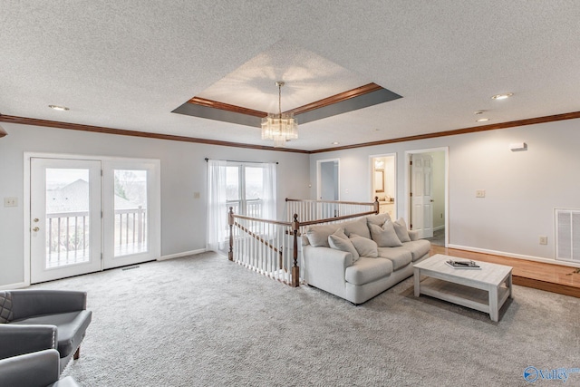 carpeted living area featuring visible vents, crown molding, baseboards, a textured ceiling, and a raised ceiling