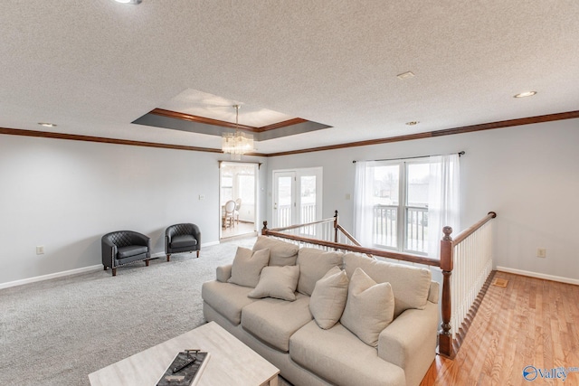 living area featuring a tray ceiling, baseboards, a textured ceiling, and crown molding