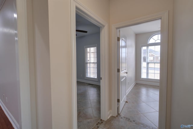corridor with light tile patterned flooring and baseboards