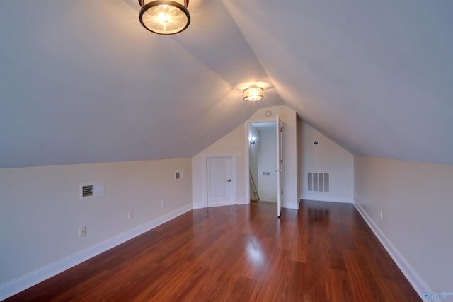 bonus room featuring baseboards, visible vents, wood finished floors, and vaulted ceiling