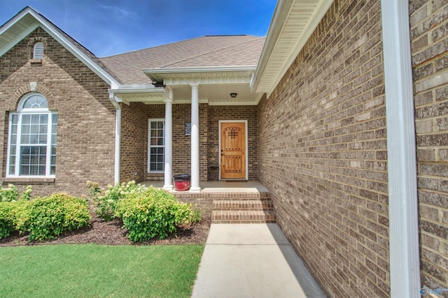 property entrance featuring brick siding and roof with shingles