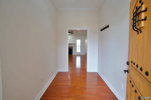 hall with crown molding, wood finished floors, and baseboards
