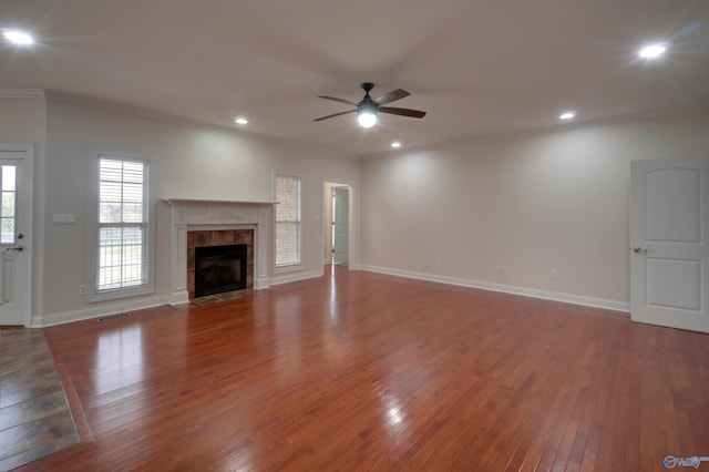 unfurnished living room with crown molding, a tile fireplace, ceiling fan, and hardwood / wood-style flooring