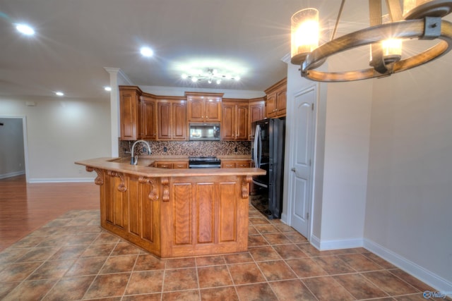 kitchen with stainless steel microwave, brown cabinets, freestanding refrigerator, range with electric stovetop, and a peninsula