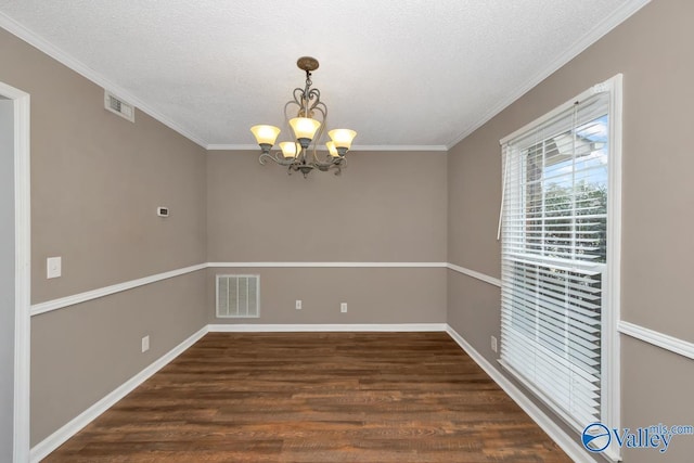 empty room featuring dark hardwood / wood-style flooring, crown molding, a textured ceiling, and an inviting chandelier