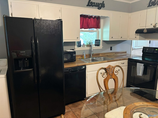 kitchen featuring light tile patterned flooring, under cabinet range hood, a sink, black appliances, and washer / clothes dryer