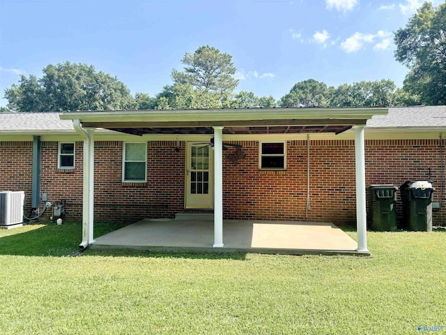 rear view of property featuring a lawn, cooling unit, and brick siding