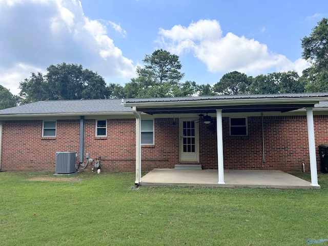 rear view of property featuring a patio area, cooling unit, a lawn, and brick siding