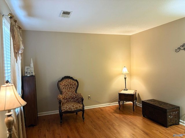 living area with wood finished floors, visible vents, and baseboards