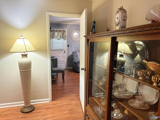 interior space with ornamental molding, baseboards, and wood finished floors