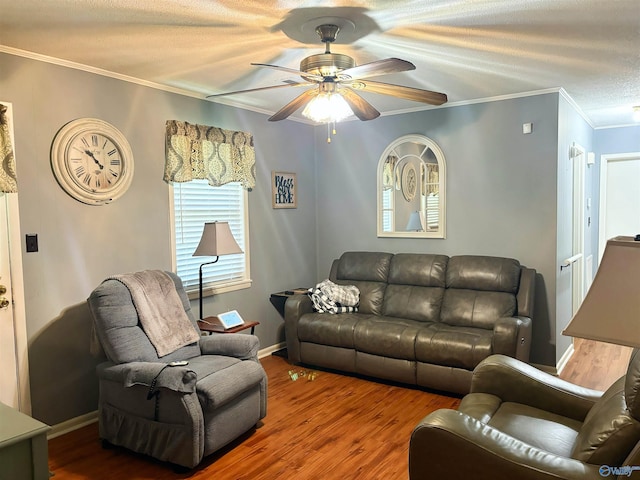 living room with ornamental molding, ceiling fan, a textured ceiling, wood finished floors, and baseboards