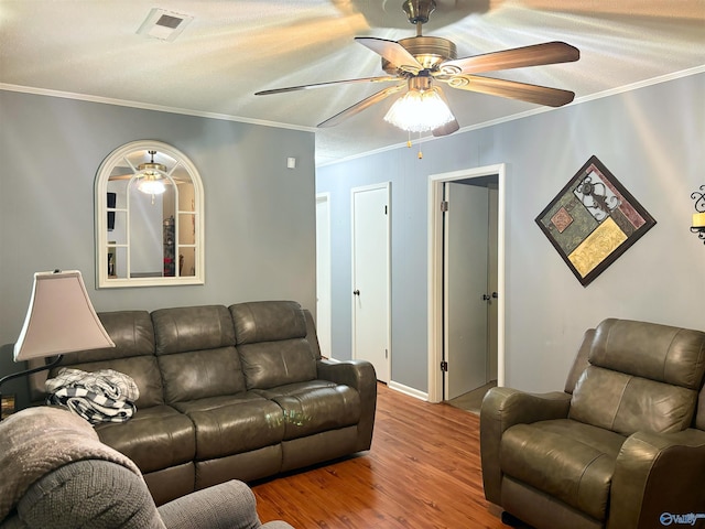 living room featuring visible vents, ornamental molding, ceiling fan, and wood finished floors