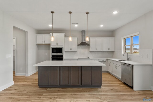 kitchen with decorative light fixtures, stainless steel appliances, a kitchen island, and light hardwood / wood-style flooring