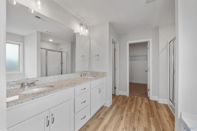 bathroom with hardwood / wood-style floors, vanity, and a shower with shower door